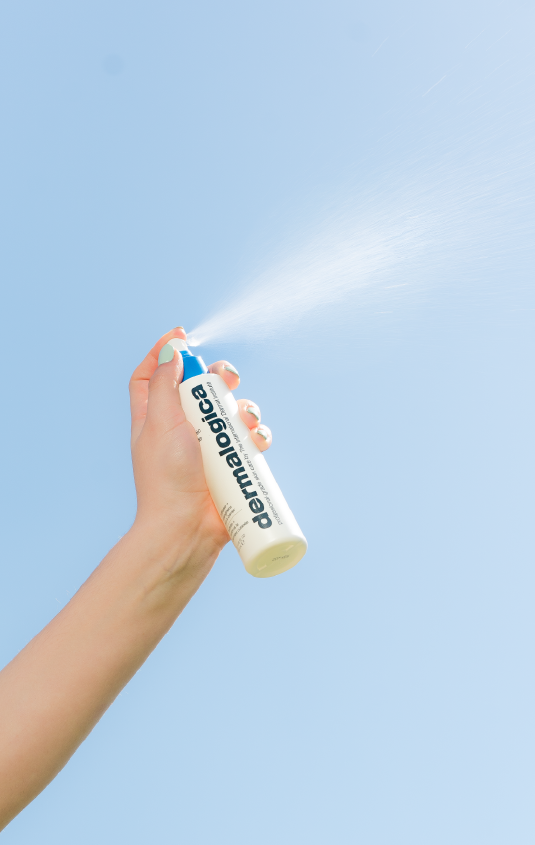 Person spraying mist from a Dermalogica bottle into the sky.