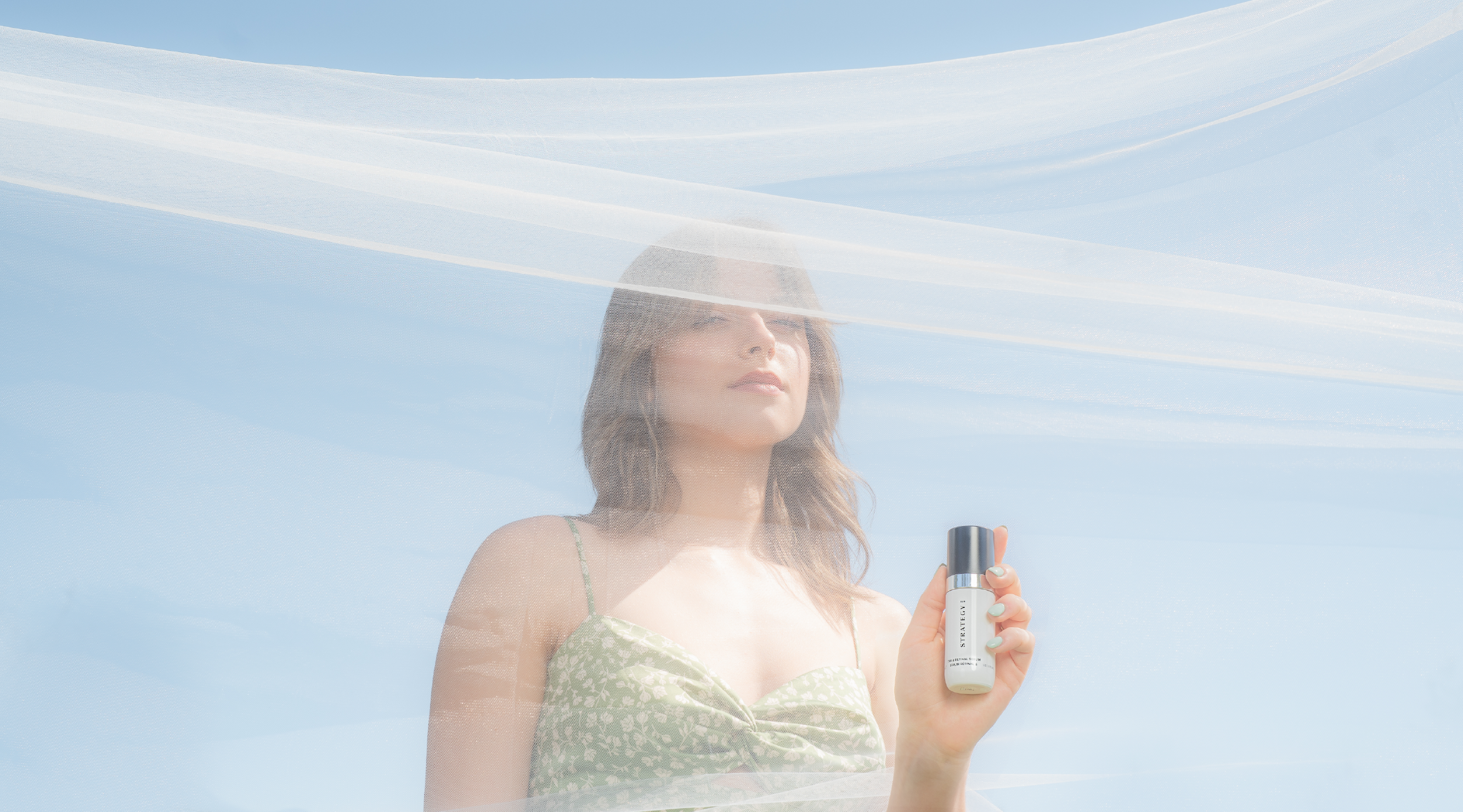 Nevaeh Day Spa: Woman standing behind wispy fabric holding a product with sky blue background.