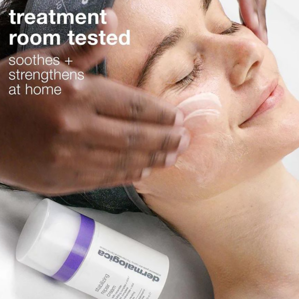 Dermalogica Stabilizing Repair Cream bottle beside a woman getting a facial.